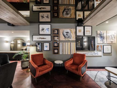 a lobby with two chairs and pictures on the wall at Mercure Hotel Pforzheim in Pforzheim