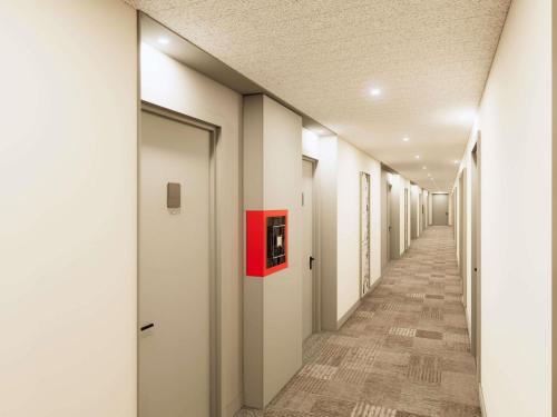 a hallway with white walls and a red box on the wall at Mercure Alba Iulia in Alba Iulia