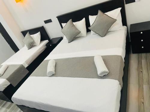 Dos camas en una habitación con sábanas y almohadas blancas. en Sinharaja Eliphinity Hotel and Restaurant, en Nikawatawana