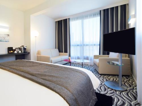 a hotel room with a bed and a flat screen tv at Kyriad Paris Ouest - Bezons La Défense in Bezons