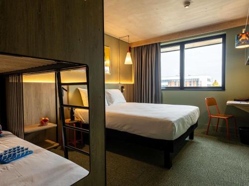 ein Hotelzimmer mit zwei Betten und einem Fenster in der Unterkunft greet Hotel Reims Tinqueux in Reims