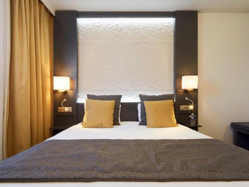a bedroom with a bed with two pillows and a window at Kyriad Paris Ouest - Bezons La Défense in Bezons