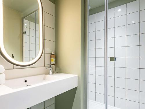 ein Badezimmer mit Waschbecken und Spiegel in der Unterkunft greet Hotel Reims Tinqueux in Reims