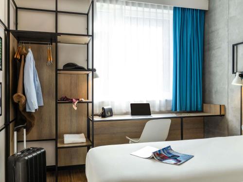 a bedroom with a bed and a desk with a laptop at ibis Bordeaux Nord Carbon Blanc in Carbon-Blanc