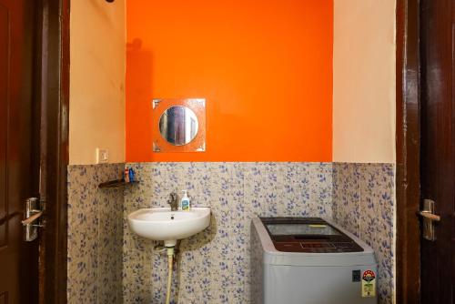 an orange bathroom with a sink and a toilet at Pretty Garden View Apartment 3BHK Furnished Flat near Kashi Vishwanath Temple in Varanasi