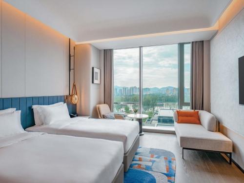 ein Hotelzimmer mit zwei Betten und einem Fenster in der Unterkunft Novotel Huzhou South Taihu Lake in Huzhou