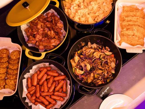 a table topped with different types of food in pans at You Hotel Budapest - Handwritten Collection in Budapest