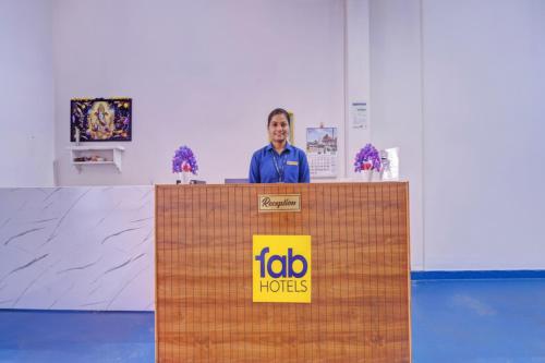 Un hombre está de pie detrás de una mesa con un cartel. en Via Lishikaas Inn, en Tākalghāt