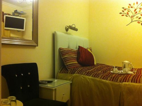 um quarto com uma cama, um espelho e uma cadeira em ABC Hyde Park Hotel em Londres