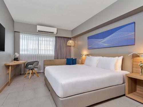Mercure Phuket Patong Journeyhub في شاطيء باتونغ: غرفة فندقية بها سرير كبير ومكتب