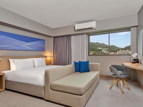 a bedroom with a bed and a couch and a desk at Mercure Phuket Patong Journeyhub in Patong Beach