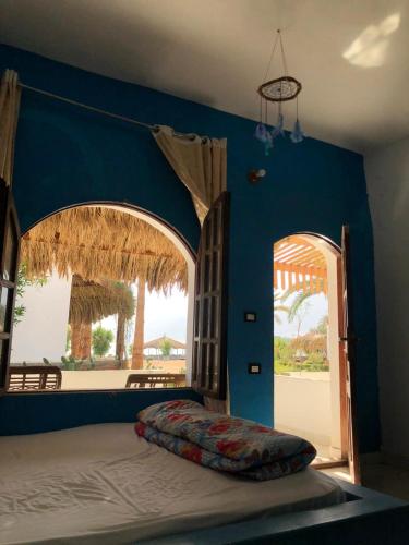 a bedroom with a bed with a blue wall at Palm Valley camp in Nuweiba‘ el Muzeinah