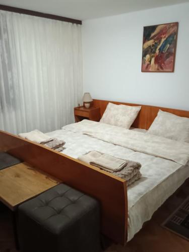 a bedroom with a large bed with a bench next to it at Vila Petrov in Lukavica