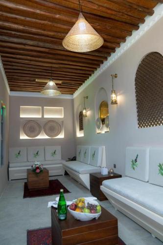 a living room with a couch and a bowl of fruit on a table at Nozol Al Rayaheen By Sharjah Collection in Khor Fakkan