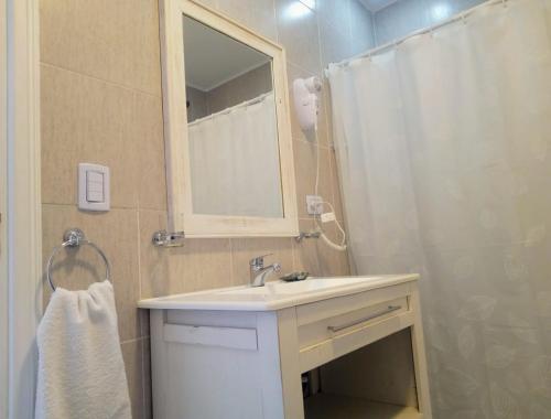 a bathroom with a sink and a shower with a mirror at Cabañas Aluen in El Calafate