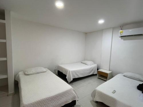 two beds in a room with white walls at casa fresh in Rodadero