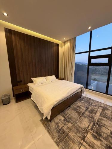 a bedroom with a large bed and a large window at albaha harmony resort in Al Baha