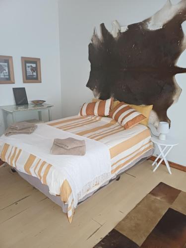 een slaapkamer met een groot bed met een schilderij aan de muur bij Bush and Birding Backpacker in Pretoria