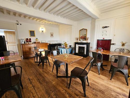 Un comedor con mesas y sillas y una chimenea. en LE MANOIR- CLUNY, en Cluny