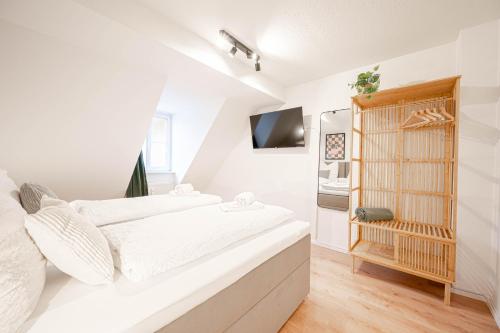a white bedroom with a bed and a tv at LudwigsCozyEscape - Historisches Altstadt-Apartment mit Sichtbalken am Residenzschloss, 6 Gäste, SmartTV in jedem Zimmer, Highspeed WLAN, Workspace, 24h Self Check-in, Parkhaus 2 Min Gehweite in Ludwigsburg