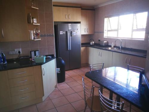 una cocina con una mesa y un refrigerador en Amery Villa, en Gqeberha