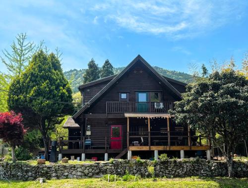 a log home with a red door and a stone wall at ログハウスSprout in Kato