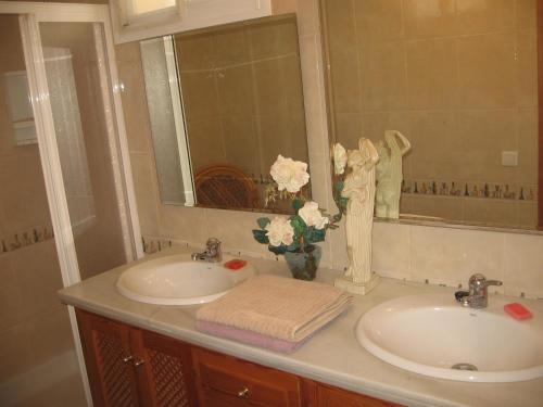 un bagno con due lavandini, specchio e fiori di Villa Roca - 1st floor a Estepona