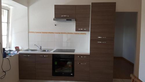 une cuisine avec des armoires en bois et un évier dans l'établissement L'écrin de l'abreuvoir, à Marnay