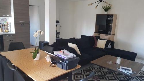 un salon avec un canapé noir et une table dans l'établissement L'écrin de l'abreuvoir, à Marnay