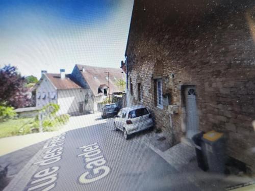 une voiture blanche garée dans une rue à côté d'un bâtiment dans l'établissement L'écrin de l'abreuvoir, à Marnay