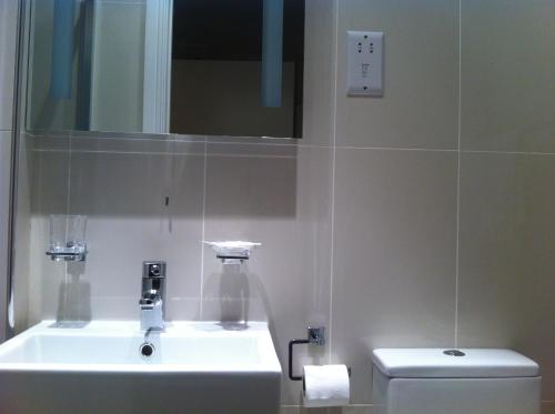 a bathroom with a sink, toilet and mirror at ABC Hyde Park Hotel in London