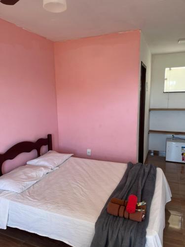 a bedroom with a white bed with a pink wall at Renascer Suites in Búzios
