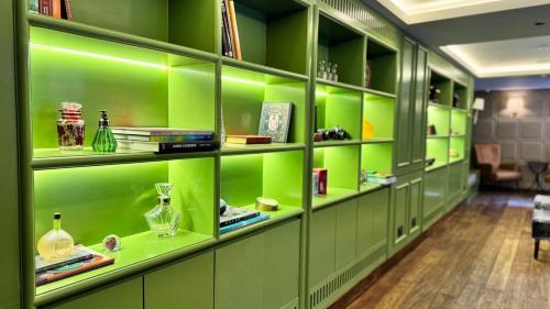 a green library with green shelves and books at Abode Jaipur in Jaipur