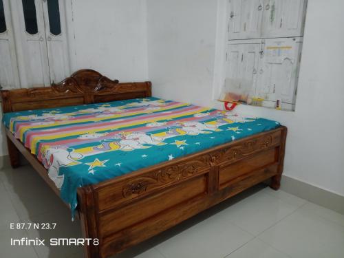 a bed with a wooden frame with a quilt on it at Swpnaneer home stay in Shānti Niketan