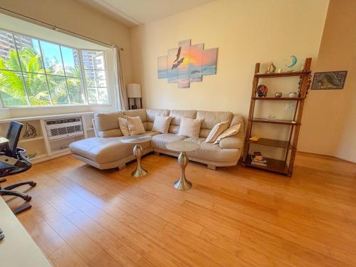 ein Wohnzimmer mit Couch und großem Fenster in der Unterkunft Hawaii Oasis 2-Bedroom at The Cove Waikiki condo in Honolulu