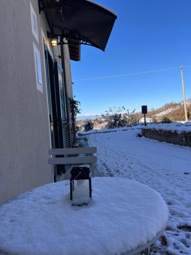 a bench sitting in the snow next to a building at Nina s Casa di Langa in Rocca Ciglie