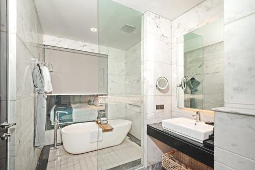 a bathroom with a tub and a sink and a mirror at JHL Solitaire Gading Serpong in Serpong