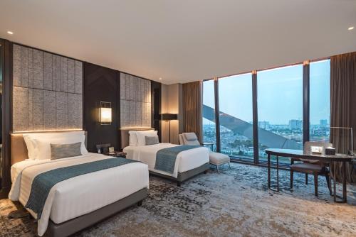 a hotel room with two beds and a desk at JHL Solitaire Gading Serpong in Serpong