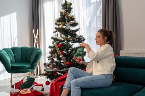 Kobieta siedząca na kanapie obok choinki świątecznej w obiekcie Bory6a Apartamenty & Free Parking w Zakopanem