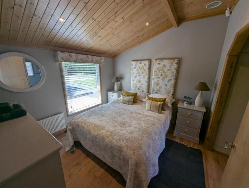 une chambre avec un grand lit et une fenêtre dans l'établissement The Boathouse Lodge, à Whelford