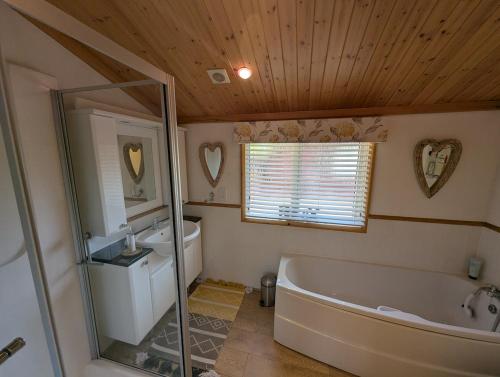 une salle de bain avec une baignoire, un lavabo et un miroir dans l'établissement The Boathouse Lodge, à Whelford