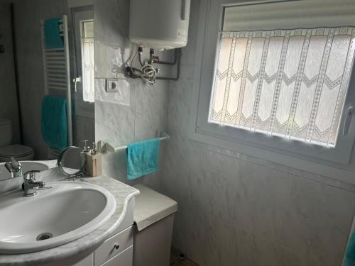 a white bathroom with a sink and a window at Casa Rural en BRAÑOSERA in Brañosera