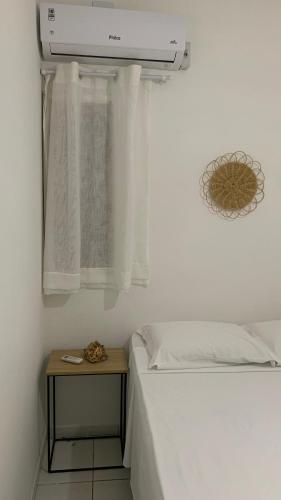 ein weißes Schlafzimmer mit einem Bett und einem Nachttisch neben dem Bett sidx sidx in der Unterkunft Casa Maria Bonita in Maragogi