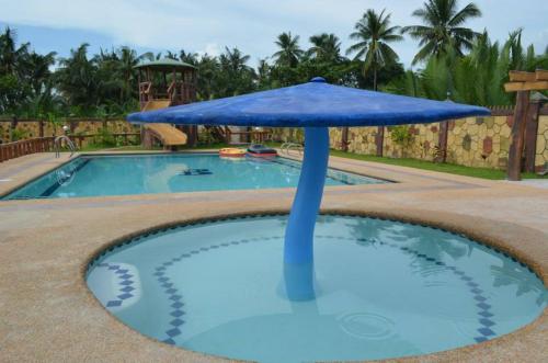 ein blauer Sonnenschirm in einem Schwimmbecken in der Unterkunft Bulls residence seaview in Toledo City