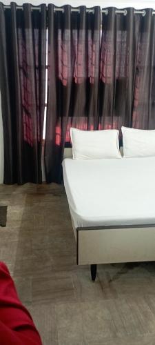 Dos camas frente a una ventana con cortinas. en Sri Raghavendra Inn, en Kākināda