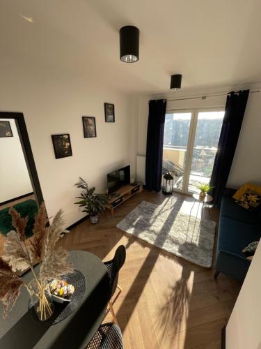 ein Wohnzimmer mit Tisch und großem Fenster in der Unterkunft Ami Luxury Residence XII CENTRUM - możliwość REJSU ŁODZIĄ in Iława