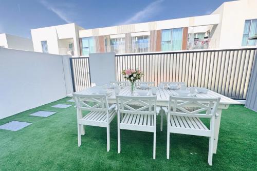 Biały stół z krzesłami i wazon kwiatów w obiekcie Amaizing Villa in a Calm Neighborhood w Dubaju