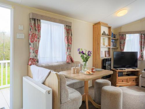 ein Wohnzimmer mit Tisch und Fernseher in der Unterkunft The Villa At Youlditch Farm in Okehampton