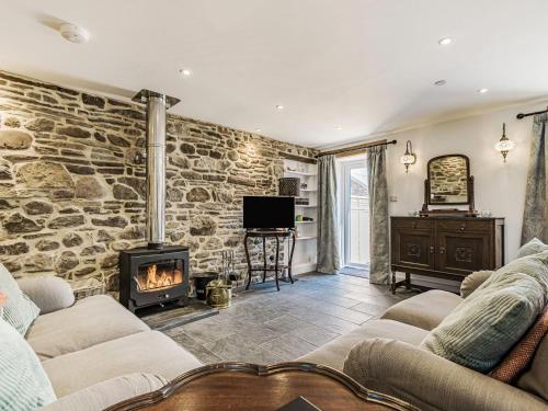 a living room with a stone wall and a fireplace at The Stables - Cottage in Bryngwyn