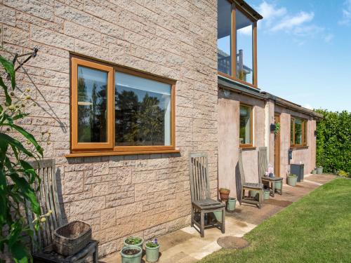 a brick house with two chairs and a window at Seashells in Dunster